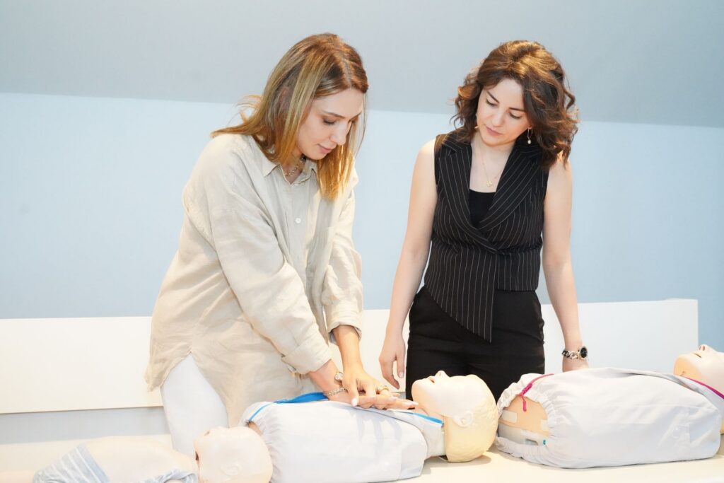 Trainer guiding a learner through CPR on a manikin